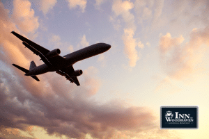 Silhouette of an airplane with a pastel pink and purple cloudy sky.