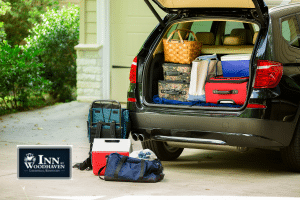 Open trunk of a silver mini van filled with boxes, suitcases and coolers.