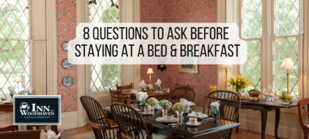 Bed and Breakfast dining room with a long dark wood table surrounded by dark wood chairs. Walls are covered in pink floral wallpaper. The table is set with white china.